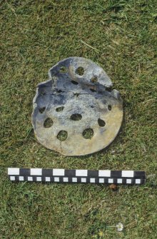 Perforated lead disc, probably part of a pump filter from the wreck-site. Scale in inches and centimetres.