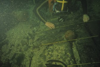 Keith Muckelroy inspects abraded elements of structure uncovered by sea-bed movement. The piece of iron shot has been removed from elsewhere on the site and is in the process of recovery.