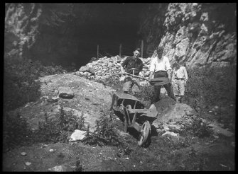 Two men and a boy standing at entrance to cave. 
Lantern slide titled: Geo. Applebey, A. McSporran, Geo. McSporran.