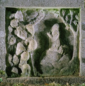 Detail of carved panel on left of well head depicting Moses praying and tetragrammaton