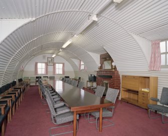 Interior view of officers mess, conference room (hut 27) showing meetings table, seating and fireplace