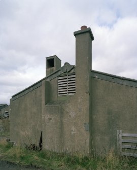 View NW of hut in accommodation camp showing detail of gable end with chimney stack and wooden louvred ventilator.