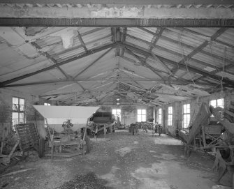 Interior view of part of the mess hall complex showing steel 'A' frame roof trusses and the remains of the asbestos ceiling insulation.