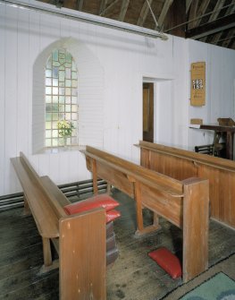 Interior. Vestry door, boarded walls, pews and window