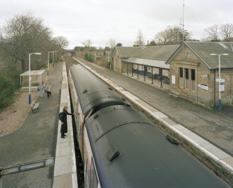 View from NW (from footbridge) showing station building and platforms, with southbound train in station