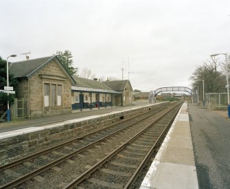 View from E of NE side of station, with tracks and platforms in the foreground, and footbridge beyond