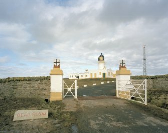View from SW of gates to compound, with lighthouse and associated buildings in background