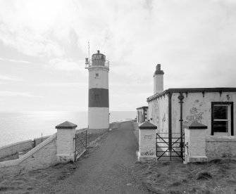 View of gate piers at entrance to compound, with lighthouse visible beyond