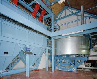 Interior.  Mash House (lower), view showing base of stainless-steel mash tun (right), and base of grist hoppers (left)