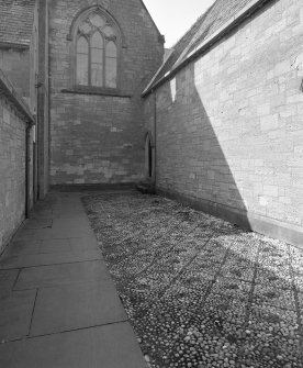 View of cobbled court outside N cloister door from E