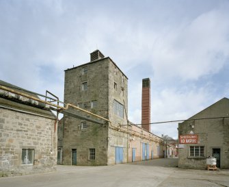 View from SW of W end of boiler-house range, with former still house in foreground, and chimney (centre)