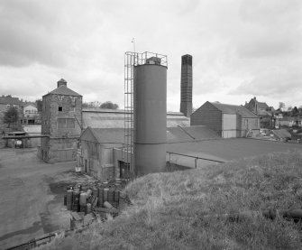 Elevated view from SW of E end of site, showing former still house (left), and boiler house block (including chimney)