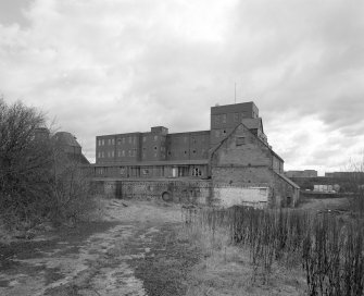 View from NNW of N side of W end of former floor maltings block, which contained barley silos.  The red saladin maltings building can be seen in the background