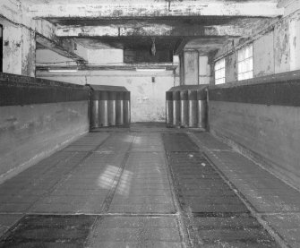 Saladin Maltings. Interior view inside an empty Saladin box, showing the steel mesh floor, concrete sides, and pair of steel gates and the far end of the box, through which the malted barley is pushed for drying in kilns once adequate germination has been achieved