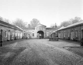 Interior view of courtyard from South West showing pedimented rear entrance, former stables and carriage houses and well
