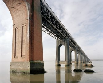 General view from SSE at water level of the E side of the bridge, also showing the foundations of the piers of the old bridge (right)