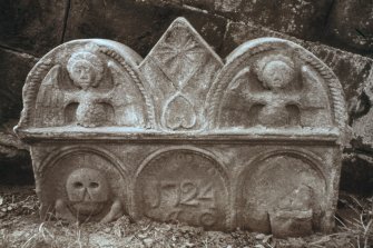 View of part buried headstone dated 1724, with angels and coulter,Clackmannan parish churchyard.
