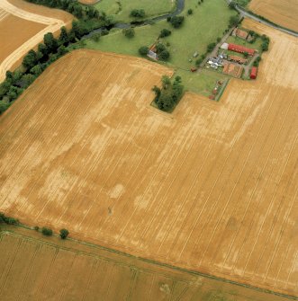 Oblique aerial view centred on the burial-ground, watermill, farmhouse, farmsteading and school, and the cropmarks of the nunnery, taken from the NE.