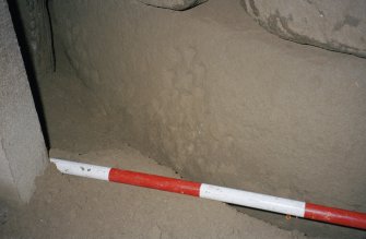 Cup-marked boulder on S side of passage