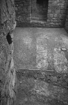 Excavation photograph : floor level within basement of tower house showing outlines of modern drains and cut for stair plinth.