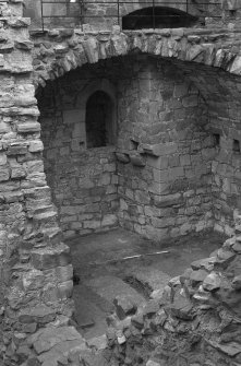 Excavation photograph : NE corner of tower house basement showing pit prison and chamber's floor partially excavated, from SW.