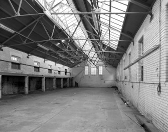 Interior view of the former wash house seen from the North, showing tiled walls and the structural metal supports of the roof.