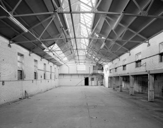 Interior view of the former wash house seen from the South, showing the tiled walls and the structural metal supports of the roof.