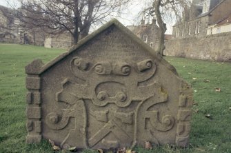 View of part buried  headstone with trade symbols, St Andrew's Cathedral graveyard.