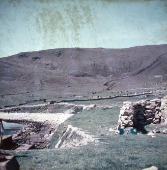 A view of the top of St Kilda's landing slip with adjacent winch and part of the manse enclosure wall, featuring a signpost to Monte Carlo.