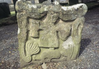 Detail of headstone with indistinct figure holding a heart and hourglass, Symington Parish Churchyard.