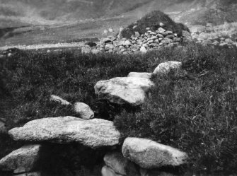 A view of the exterior of the Iron Age souterrain on Hirta, St Kilda, looking over the entrance to cleit 70 beyond. This image was sent to RCAHMS by a Captain Grant, 1924. 

