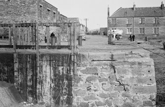 View of Cockenzie harbour wall with houses in background.
