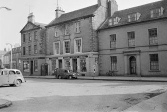View of 47-50 Market Square, Duns, from north showing the premises of R J Glover Ladies and childrens outfitter, A & G Anderson Ltd and Geo Jeffrey Stationer and Printer