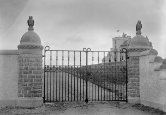 View of wrought iron entrance gates to Kinpurnie Castle with thistle motif and carved owls on gate piers