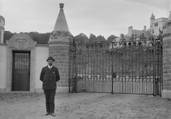 View of man standing in front of wrought iron entrance gates to Kinpurnie Castle