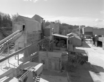 Elevated view from NE (at middle level of shaft kilns) of W end of lime works, showing part of dryer and hammer mill (left), and ball mills in background (centre)