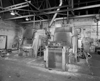 Motherwell, Craigneuk Street, Anderson Boyes
Heat Treatment (Dept. 12, west bay built 1945): Interior view from north east in west bay, showing two Ipsen sealed quench heat-treatment furnaces (TQ 7 left, and TQ 9 right).  Both are fired by pure endothermic gas from an adjacent gas producer.  Heat treatment is required for the hardening of components of machines, such as gears.  The furnaces are loaded from a rail-mounted conveyor (foreground).