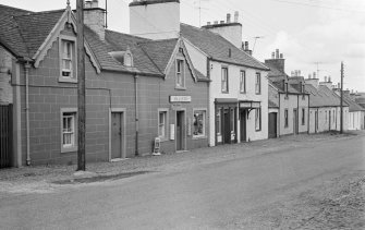View of north side of Victoria Street, Kirkpatrick Durham, from south west, showing the Crown Hotel and R McAllister's shop (no.8)