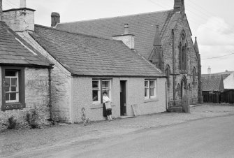 View of north side of Victoria Street, Kirkpatrick Durham, from south west showing Victoria Cottage and the Free Church and a woman with child
