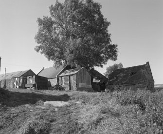 General view from E of wooden sheds on SE side of mill, and NE wing of mill with collapsed slate roof.