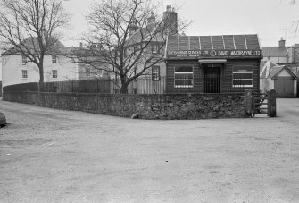 View of garden wall, Fern Point House, Inveraray, with the premises of British Road Services Ltd, Argyll Branch, David MacBrayne Ltd showing