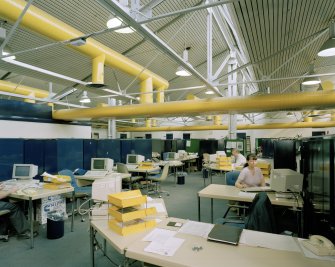 Interior view of office area, within which yellow in/out trays match overhead ducts.