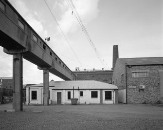 Newtongrange, Lady Victoria Colliery, Time Office and Lamp Station (Former Cement Store)
View from east of pit-head buildings, showing (left to right) overhead walkway, time office and lamp station (the former cement store) (centre), New Visitor Centre (formerly the New Power Station) (background), and the British Coal archive (formerly the colliery workshop) (right), with boilerhouse chimney in background