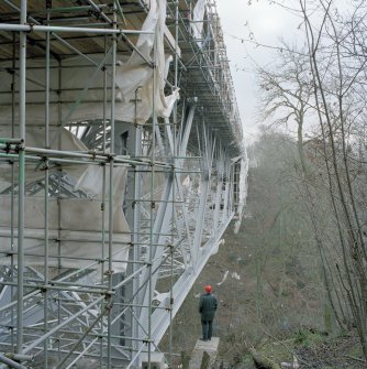 Oblique view from NNW of W side of bridge during re-furbishment, with human figure for scale.