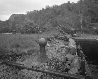 Inverfarigaig Pier
View from north west along south-west side of pier, showing a typical cast-iron bollard (foreground), and the collapsing concrete facing, beyond which is the original rubble portion of the pier