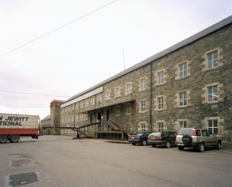Selkirk, Dunsdale Haugh, Dunsdale Road, Riverside Mills
View from north east of south east side of original spinning mill, with the engine-house in the background. At the time of the survey, the mill was used predominantly as a warehouse, and a mobile chute can be seen permitting the rapid loading of lorries, one of which is visible (left)
