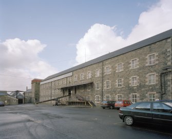 Selkirk, Dunsdale Haugh, Dunsdale Road, Riverside Mills
View from north east of south east side of original spinning mill, with the engine-house in the background. At the time of the survey, the mill was used predominantly as a warehouse, and a mobile chute can be seen permitting the rapid loading of lorries
