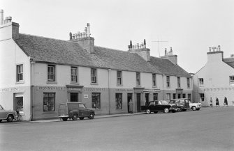 View of houses on west side of Colchester Square, Lochgilphead, from south east, showing the premises of D MacBrayne iron monger and cycle agent and C McColl grocer.