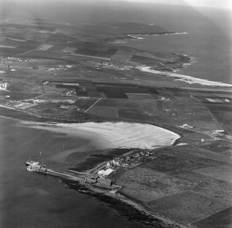 Oblique aerial view centred on Pierowall harbour and Gill Pier, Westray, Orkney, looking towards Noup Head lighthouse.