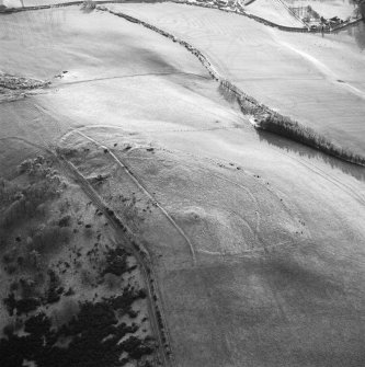 Oblique aerial view centred on the remains of the fort, settlement and cairn, taken from the N.